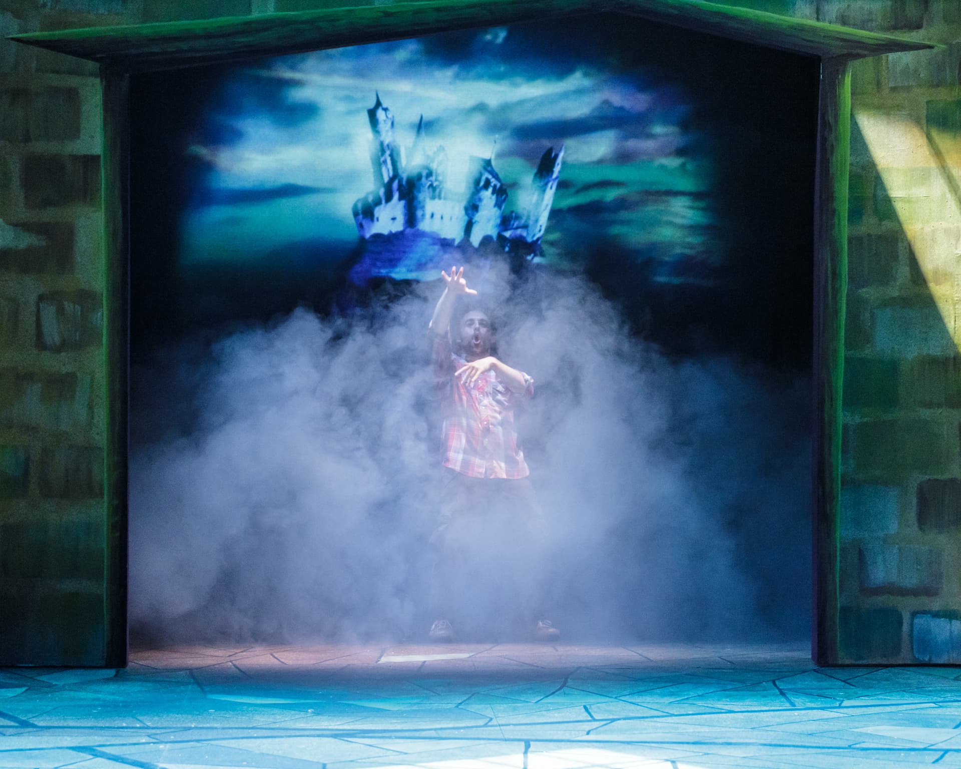 The Understudy — actor engulfed in fog beneath the projected castle